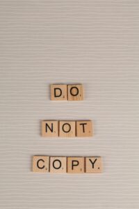 Scrabble tiles arranged as 'Do Not Copy' on a neutral background, conveying originality message.